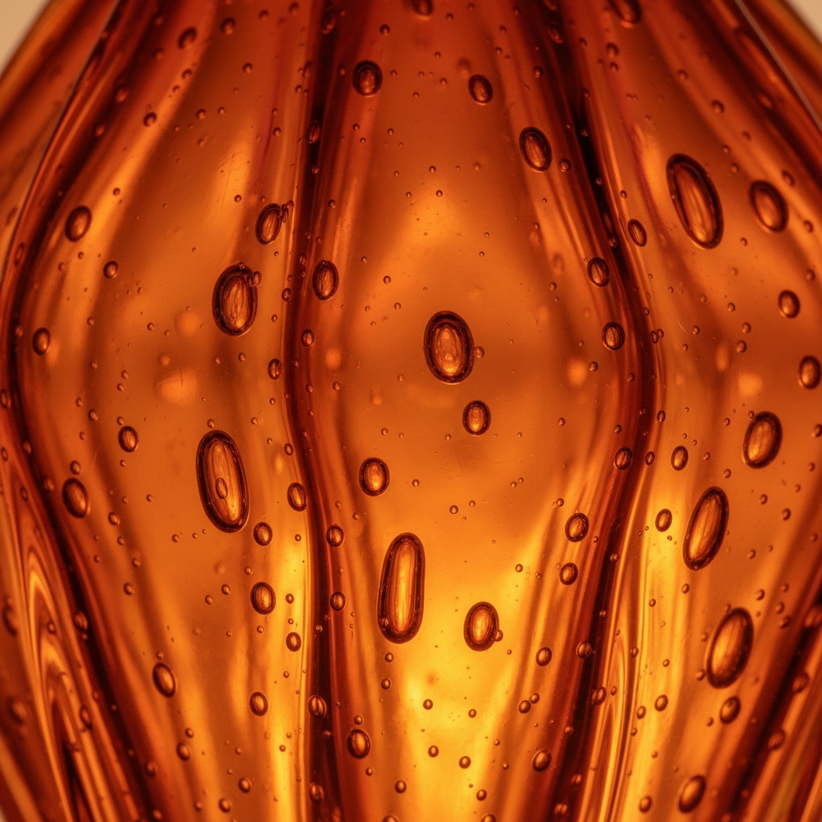 Close-up detail of hand-blown Murano amber glass texture with air bubbles and color depth